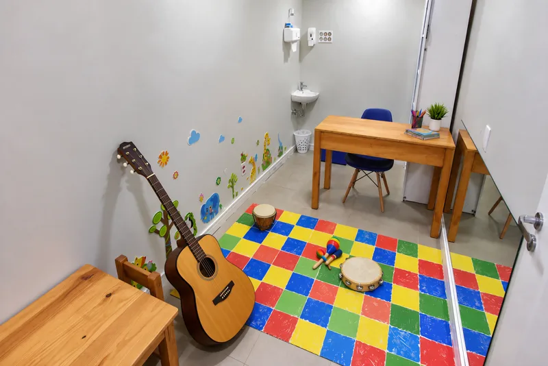 Violão, tambor, maracas e pandeiro sobre o tapete colorido da sala de musicoterapia