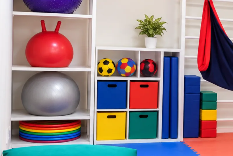Estante com bolas terapêuticas e argolas coloridas da sala de integração sensorial