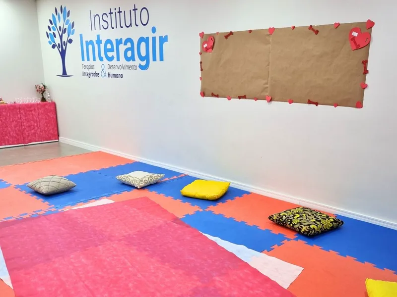 Sala do Instituto Interagir preparada para o encontro do grupo, com tatames coloridos, almofadas e um painel decorado com corações
