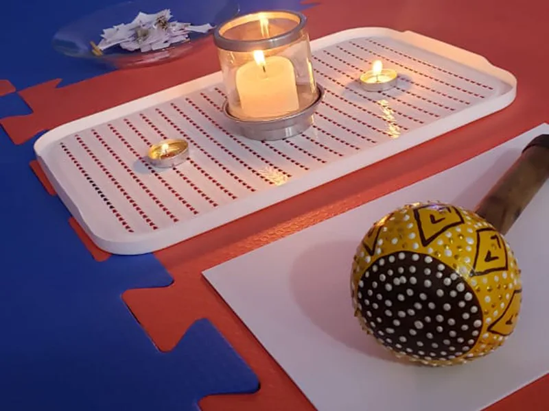 Detalhe da roda: bandeja com velas acesas, papéis com mensagens e um chocalho pintado à mão sobre o tatame