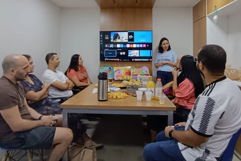 Encontro do grupo em sala do Instituto, com facilitadora em pé e famílias em volta da mesa