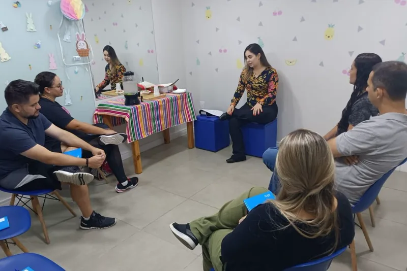 Pais e responsáveis em roda de conversa conduzida por psicóloga na sala do Instituto